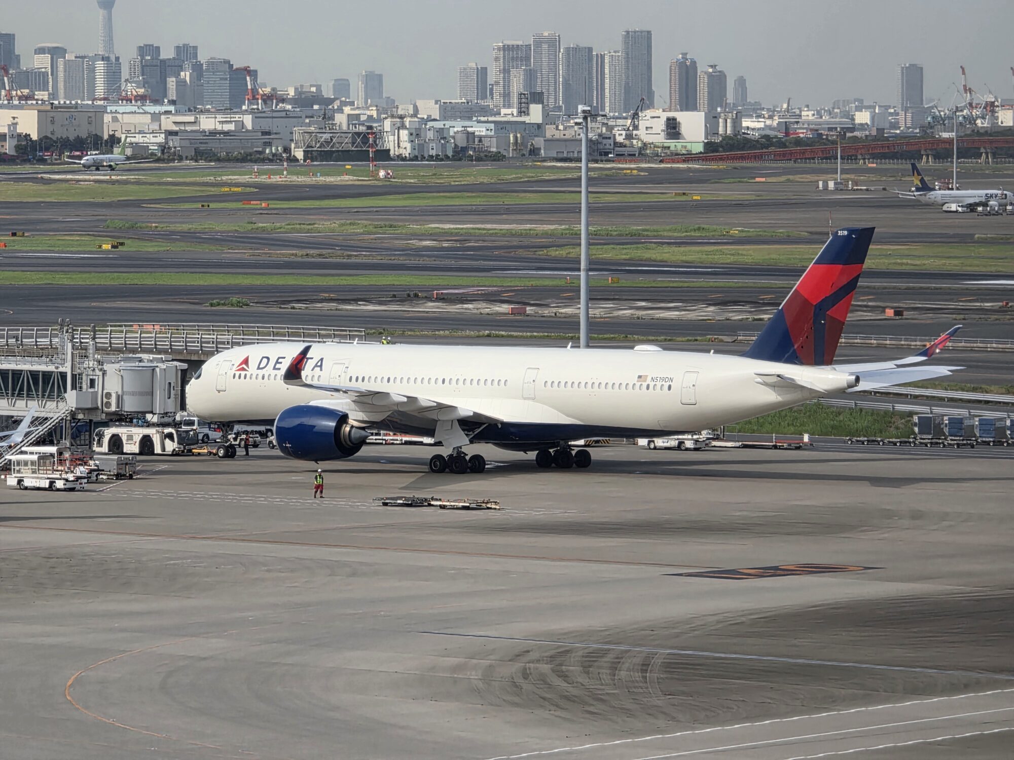 A white Delta Air Lines Airbus A350 with a red and blue tail parked at a gate at Tokyo Haneda Airport