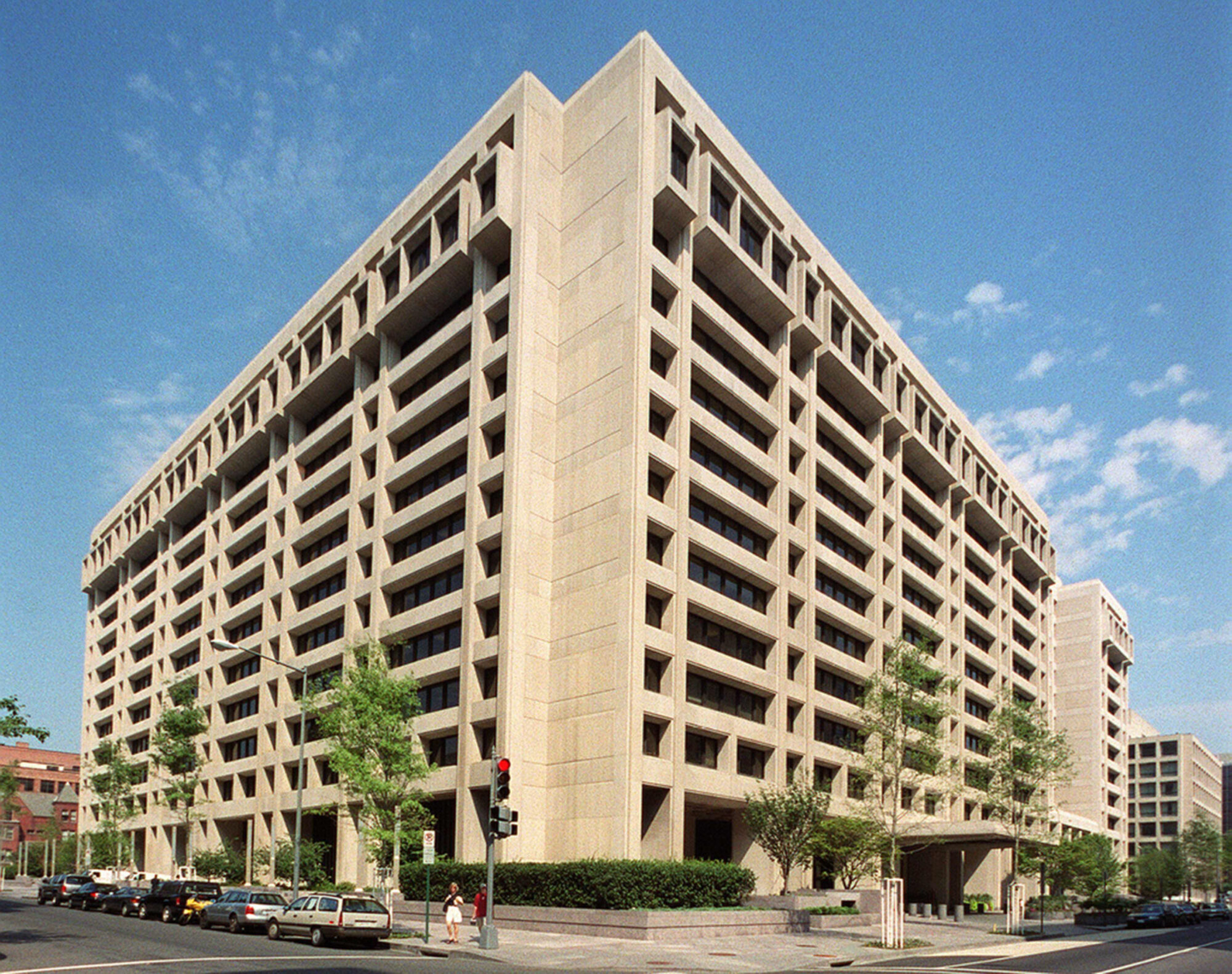 The concrete IMF headquarters building in Washington, DC, seen from a street corner under a blue sky